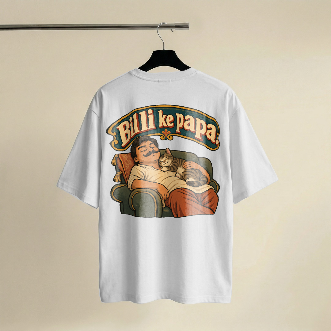 Fat arched hand-painted signboard lettering reading Billi ke papa in deep teal with red and mustard shadowing, above a flat painted scene of a moustached man asleep on a sofa with a tabby cat asleep on his chest, both drawn with the same contented closed-eye face, cream ground with bold black outlines throughout, on a white oversized t-shirt